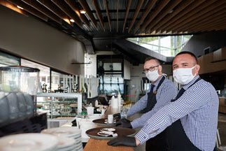 Employees wearing facemasks at a small restaurant get ready to serve customers.