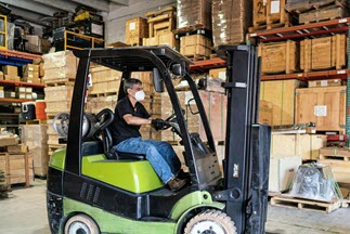 A man drives a forklift at a warehouse.