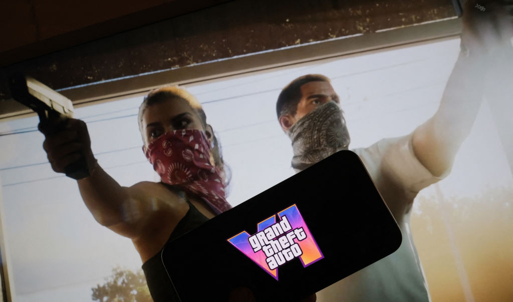 A photo illustration shows two video game characters in masks pointing guns while another screen shows the GTA VI logo.