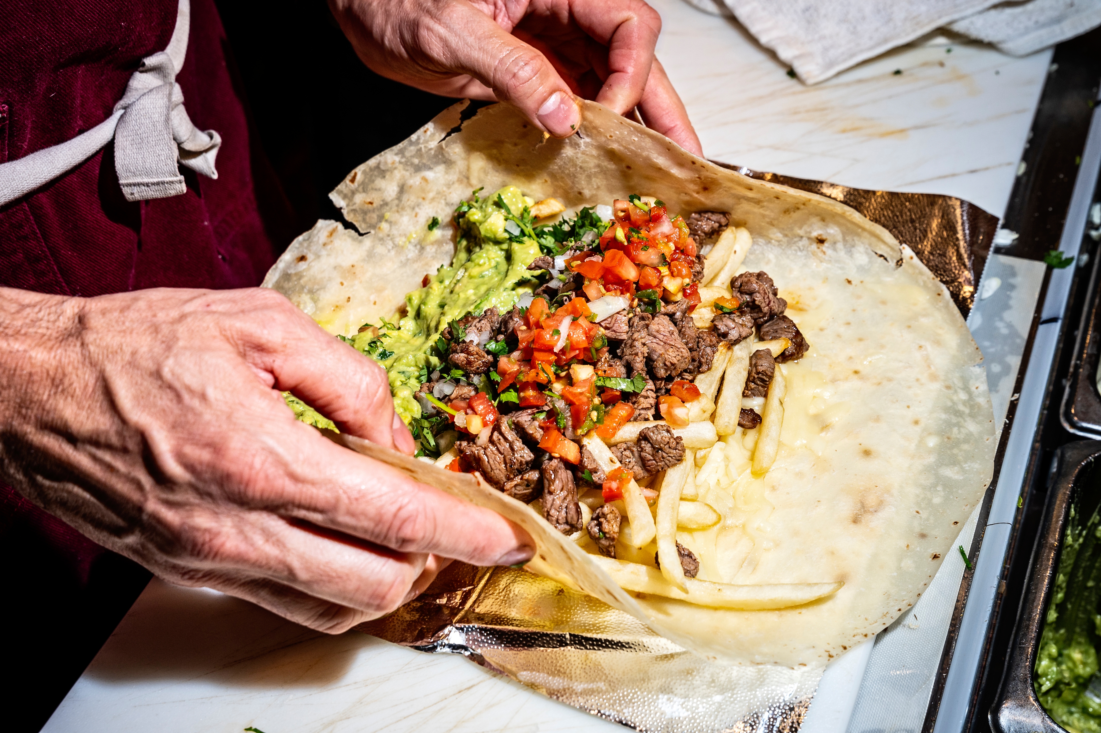 A man prepares a burrito