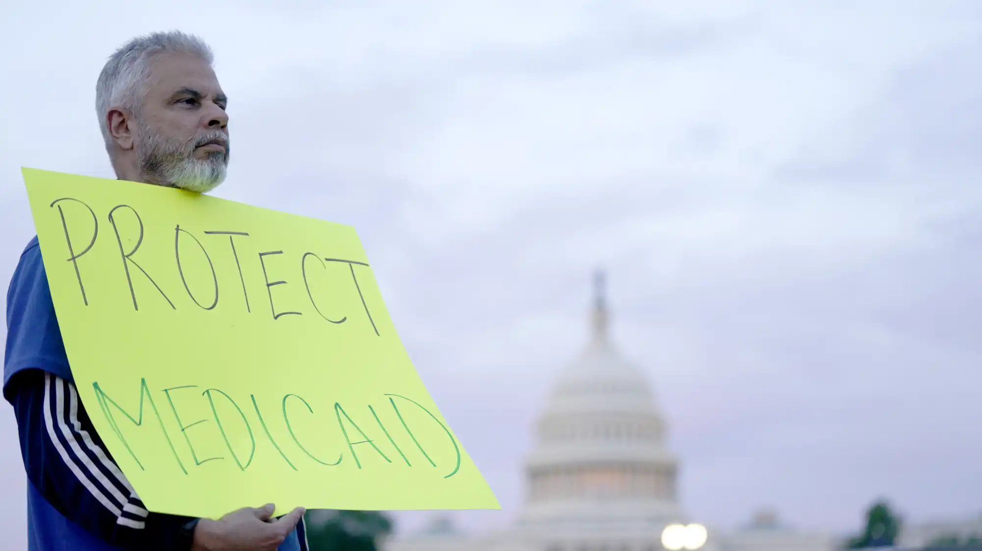 A man holds a protest sign reading 