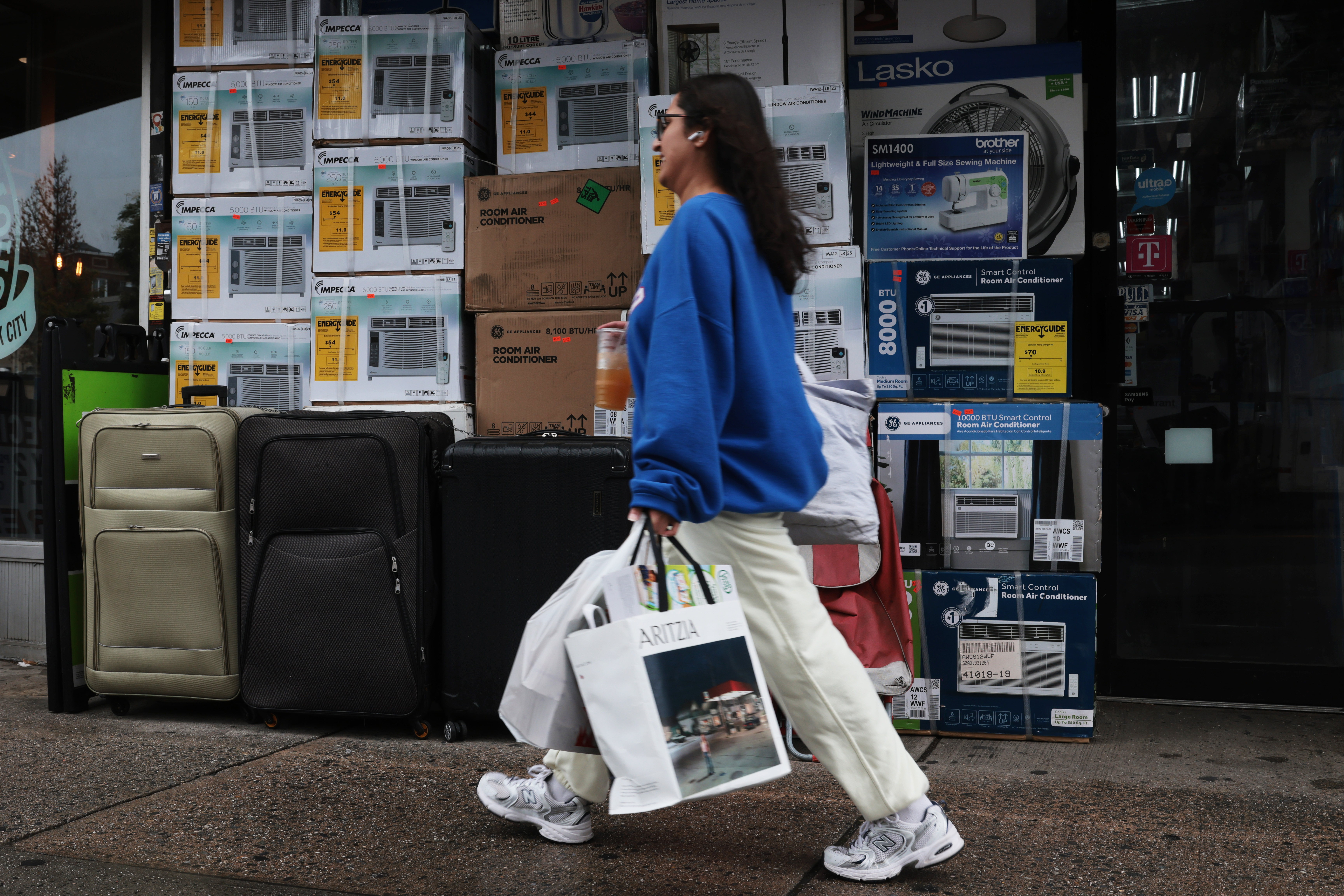 A woman walks by a store with shopping bags.