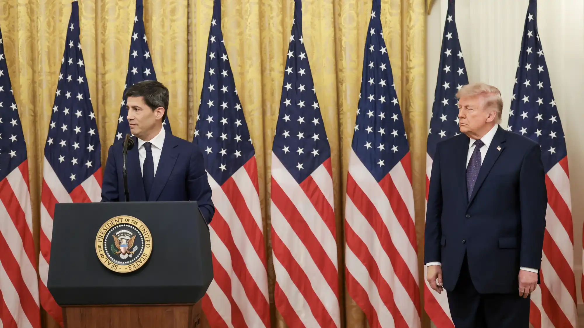 Federal Reserve chair Kevin Warsh stands at a White House lectern while President Donald Trump looks on.