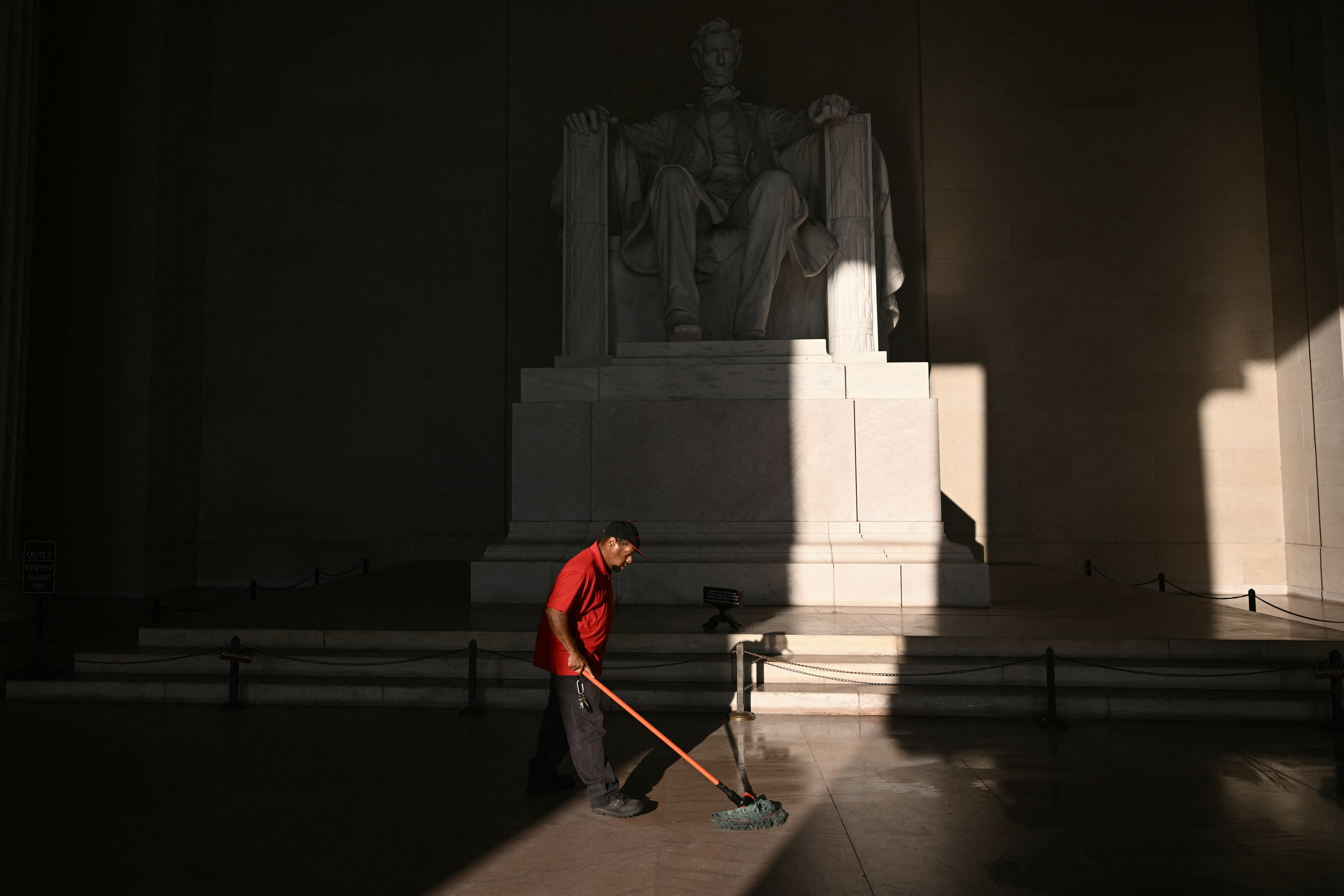 A custodian mops around the Lincoln Memorial.
