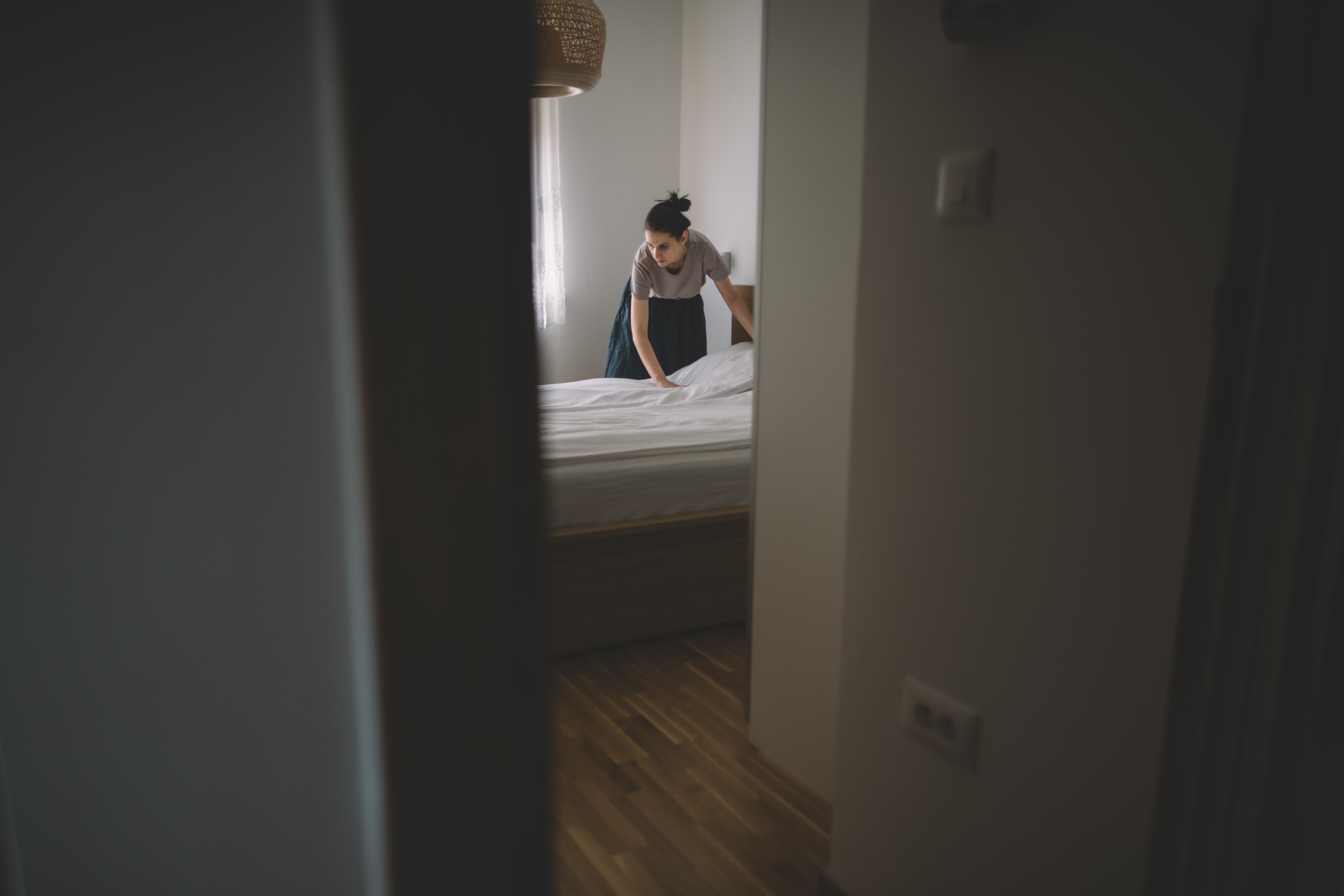 A stock photo of a woman changing the sheets on a bed.