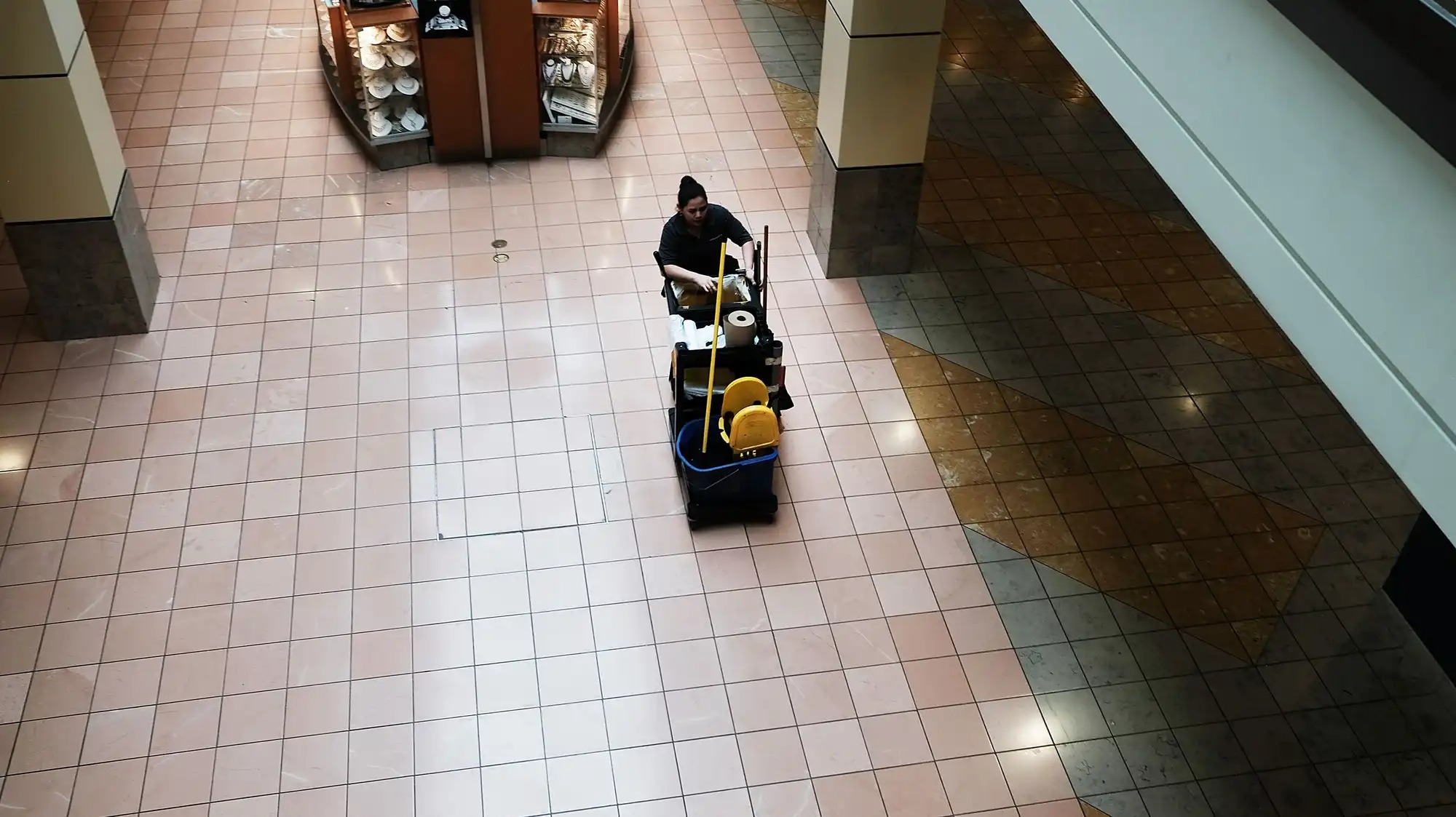 A janitor seen from above in an empty commercial space.