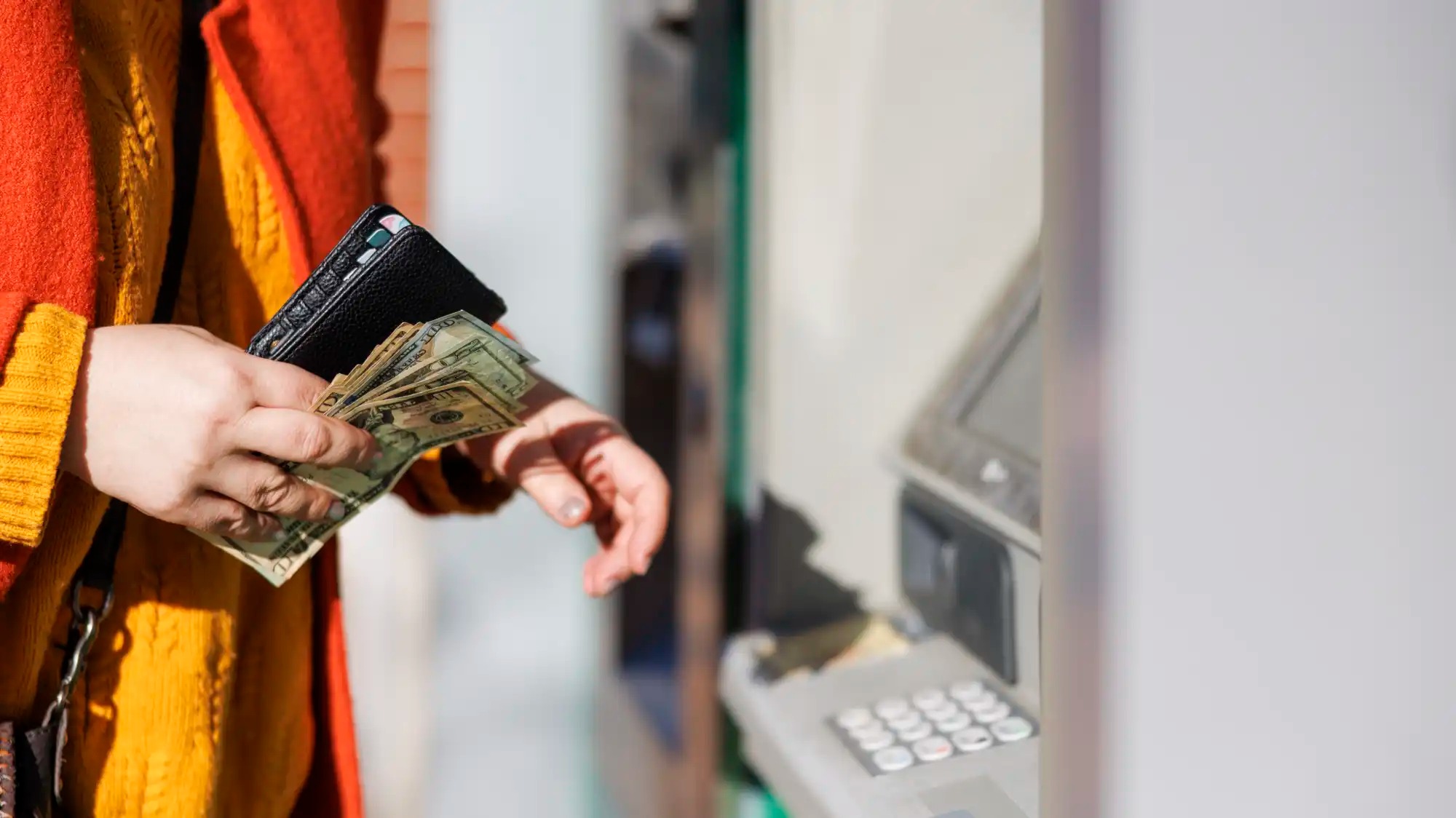 A woman takes cash out of an ATM.