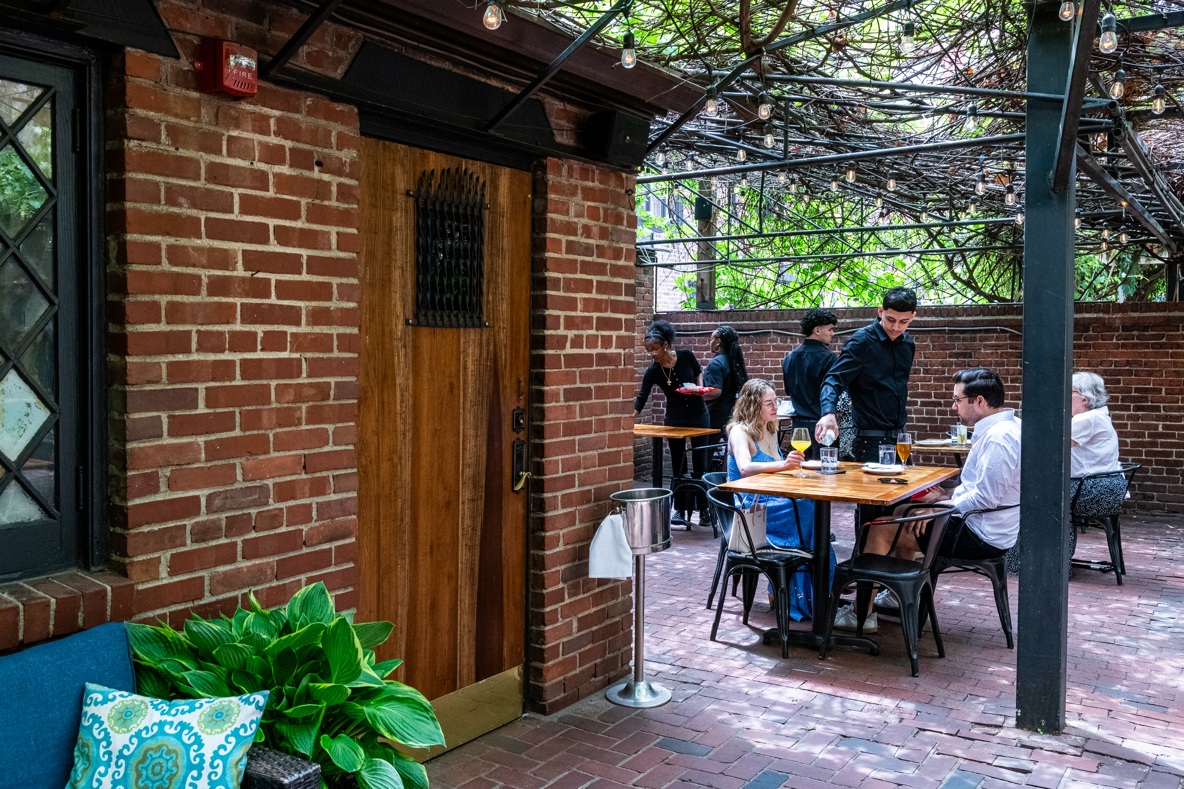 Atmosphere on a restaurant patio. A waiter pours water.