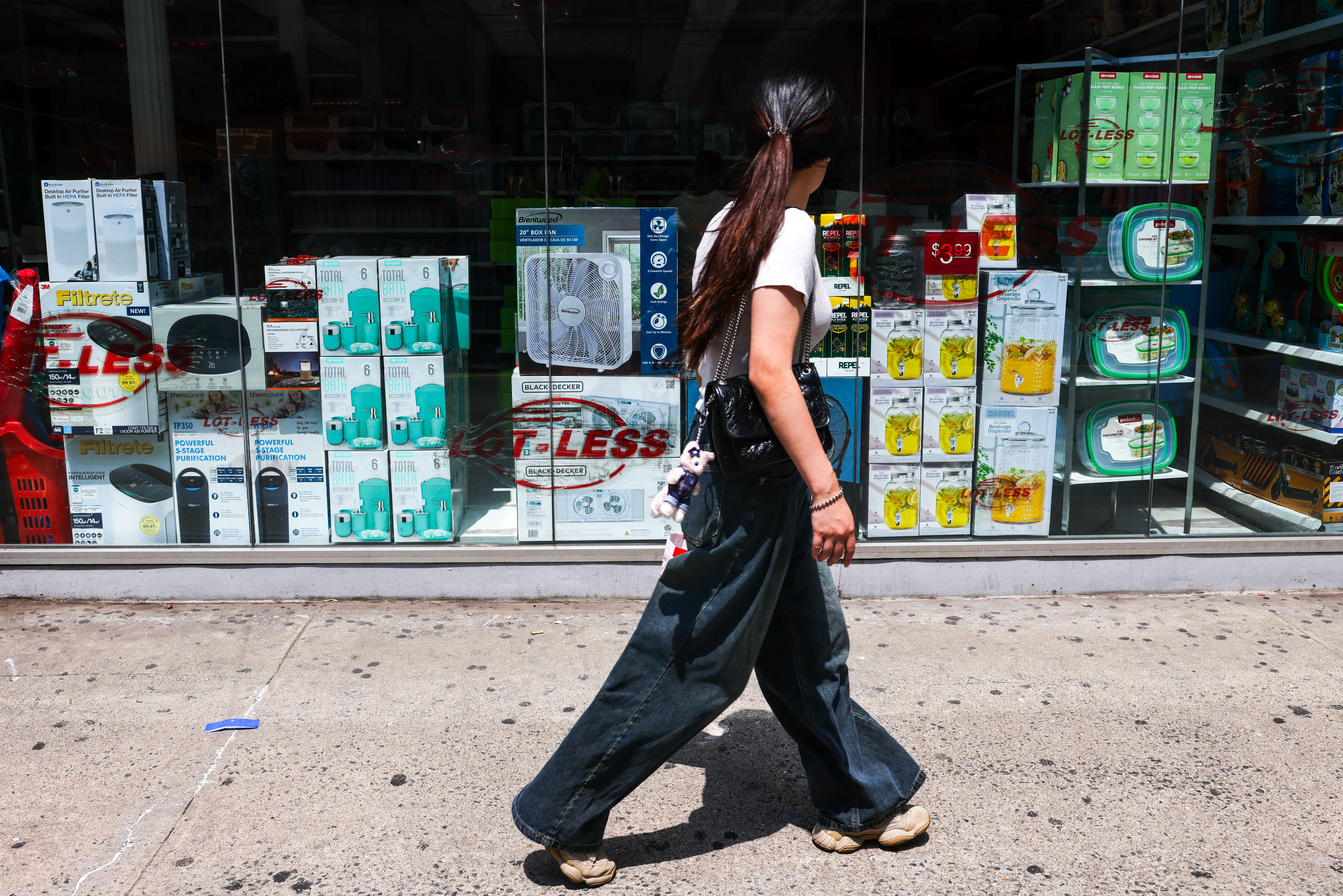 A woman walks by a store with merchandise on display.