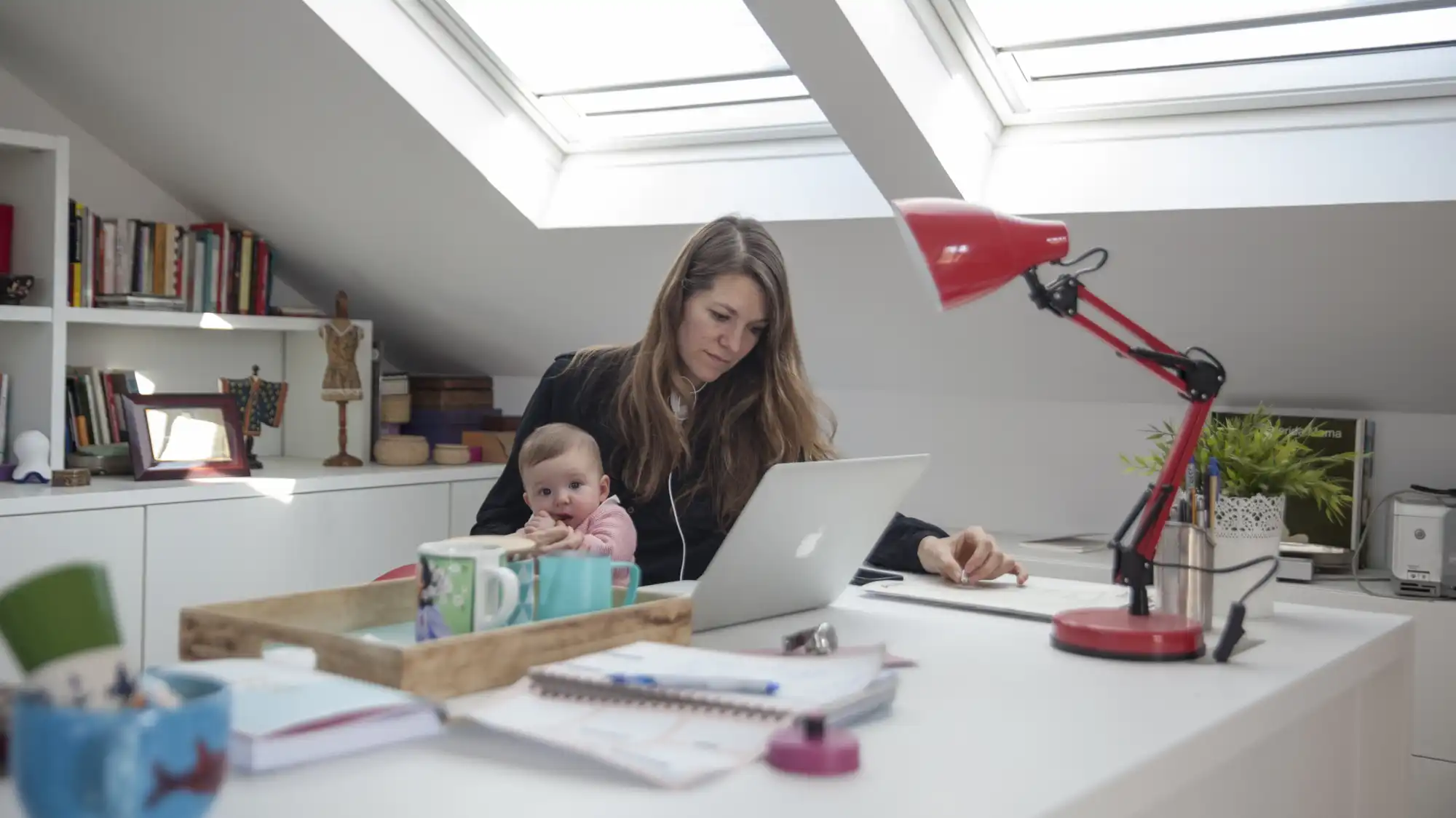 A woman works while holding a baby.