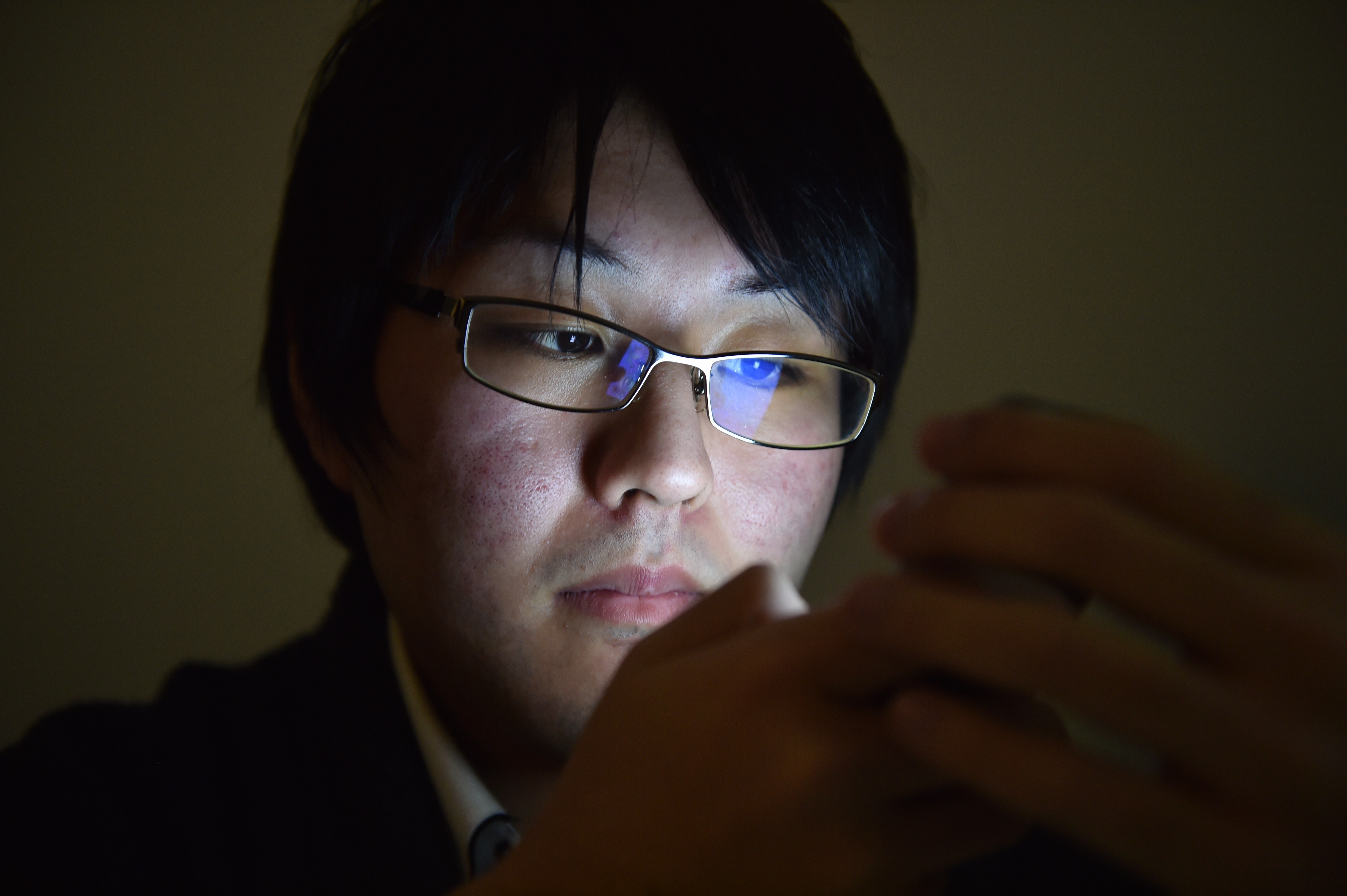 A man's face lit by a smartphone screen.