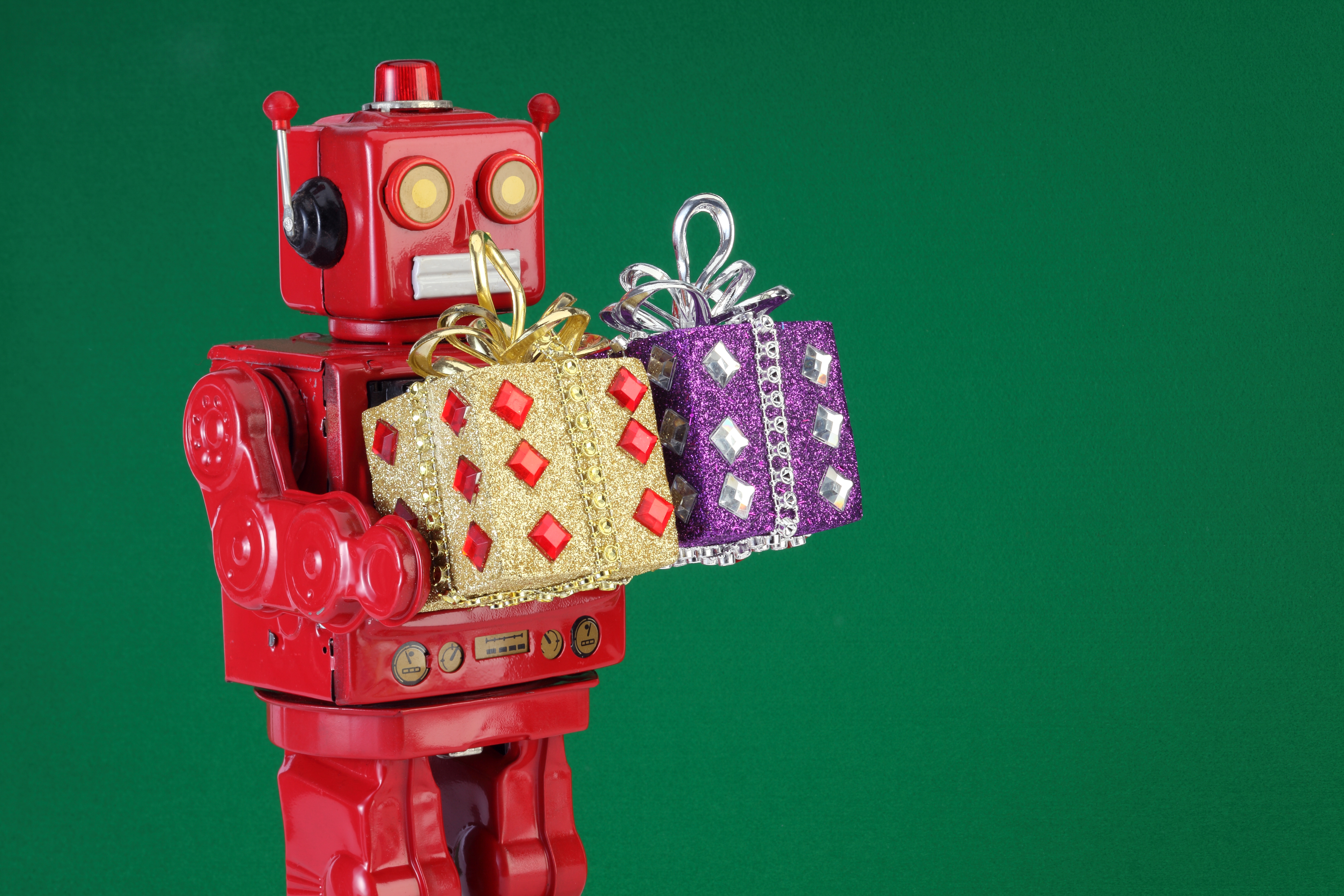 A stock photo of an old-fashioned wind-up robot holding wrapped gifts.