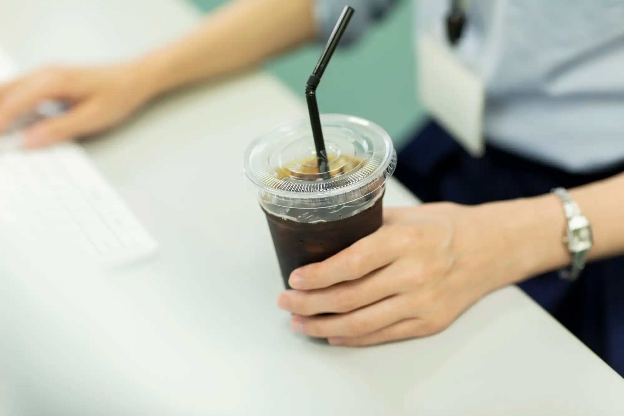 A stock photo of an office worker with an iced coffee.
