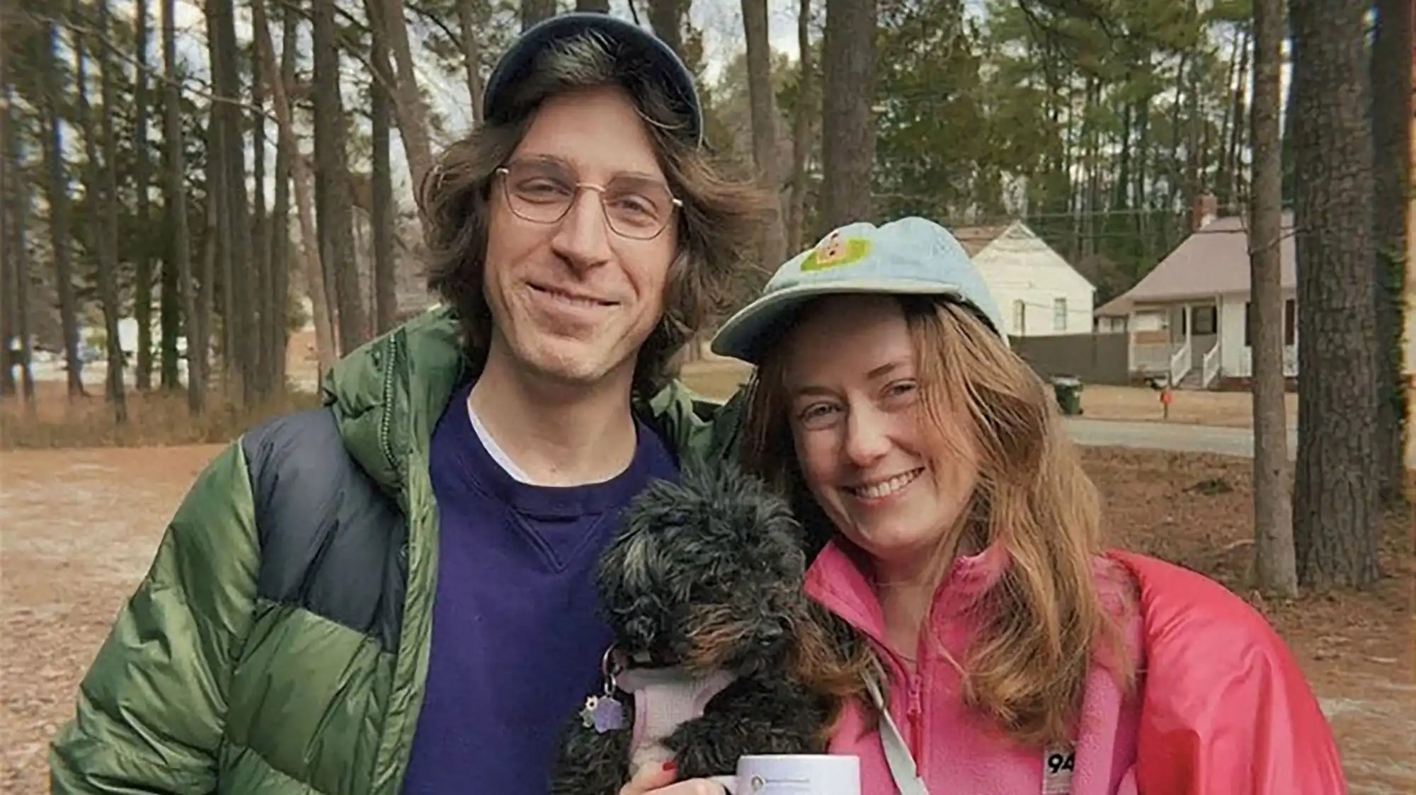 A couple posts for a photo with a small black dog.