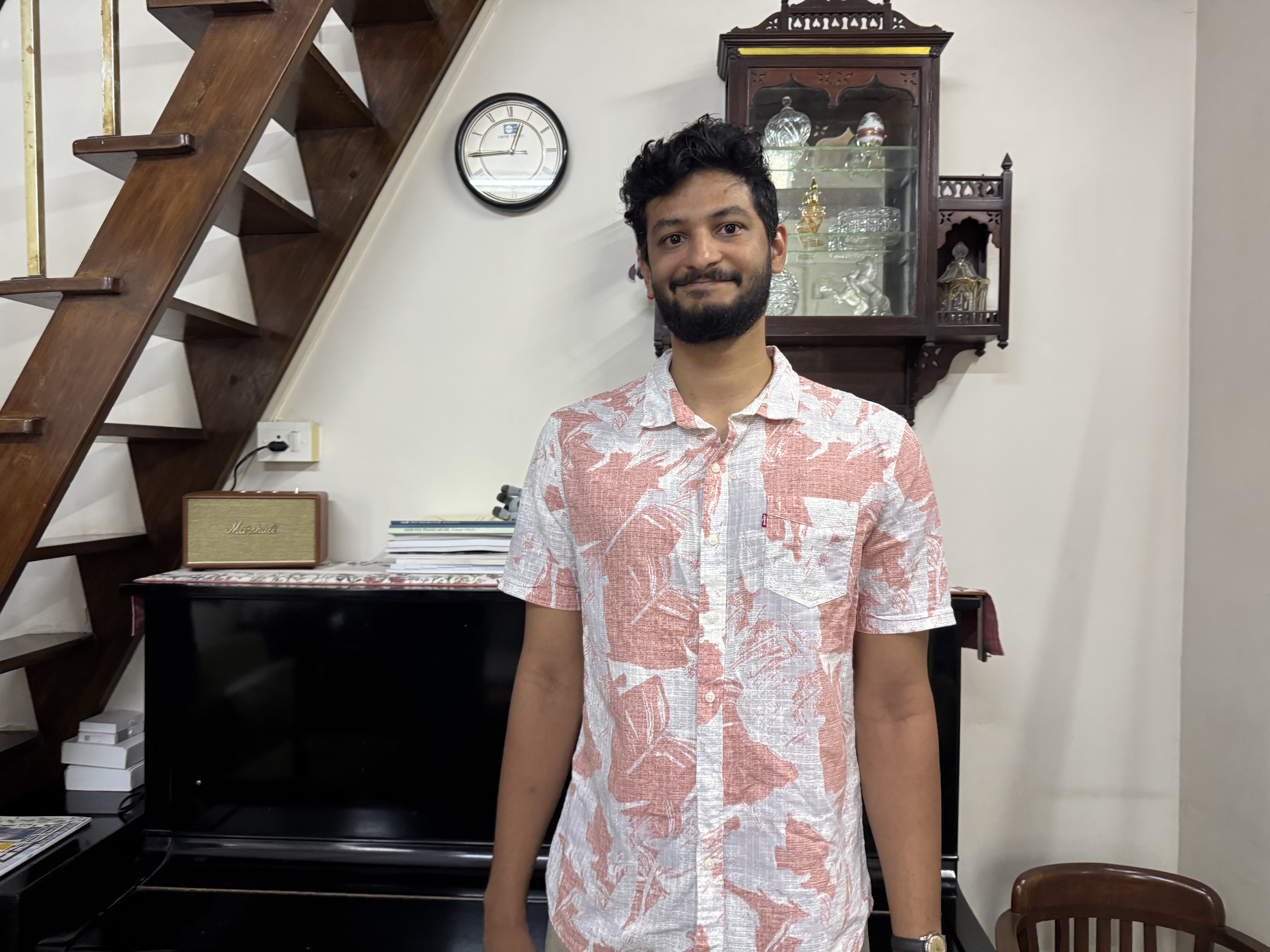 A young man with a beard and tropical shirt poses for a portraid.