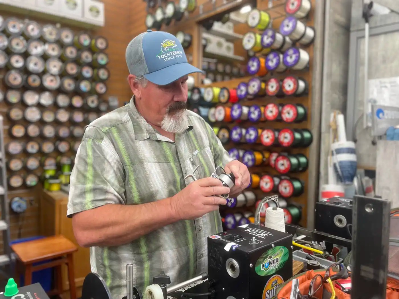A man holds spools fishing line behind a counter.