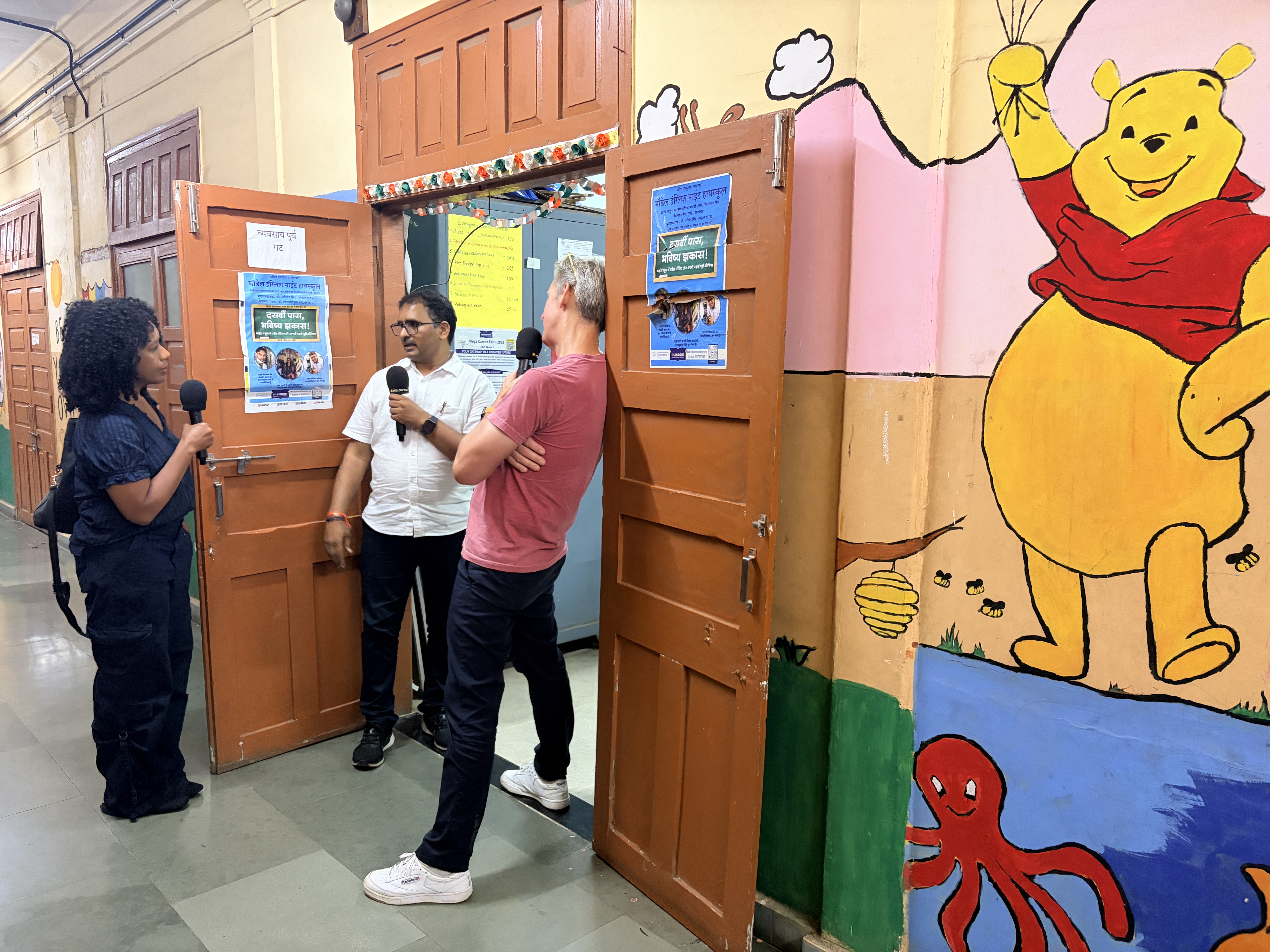 Kai Ryssdal and Nela Richardson interview a man at a school in Mumbai, India.