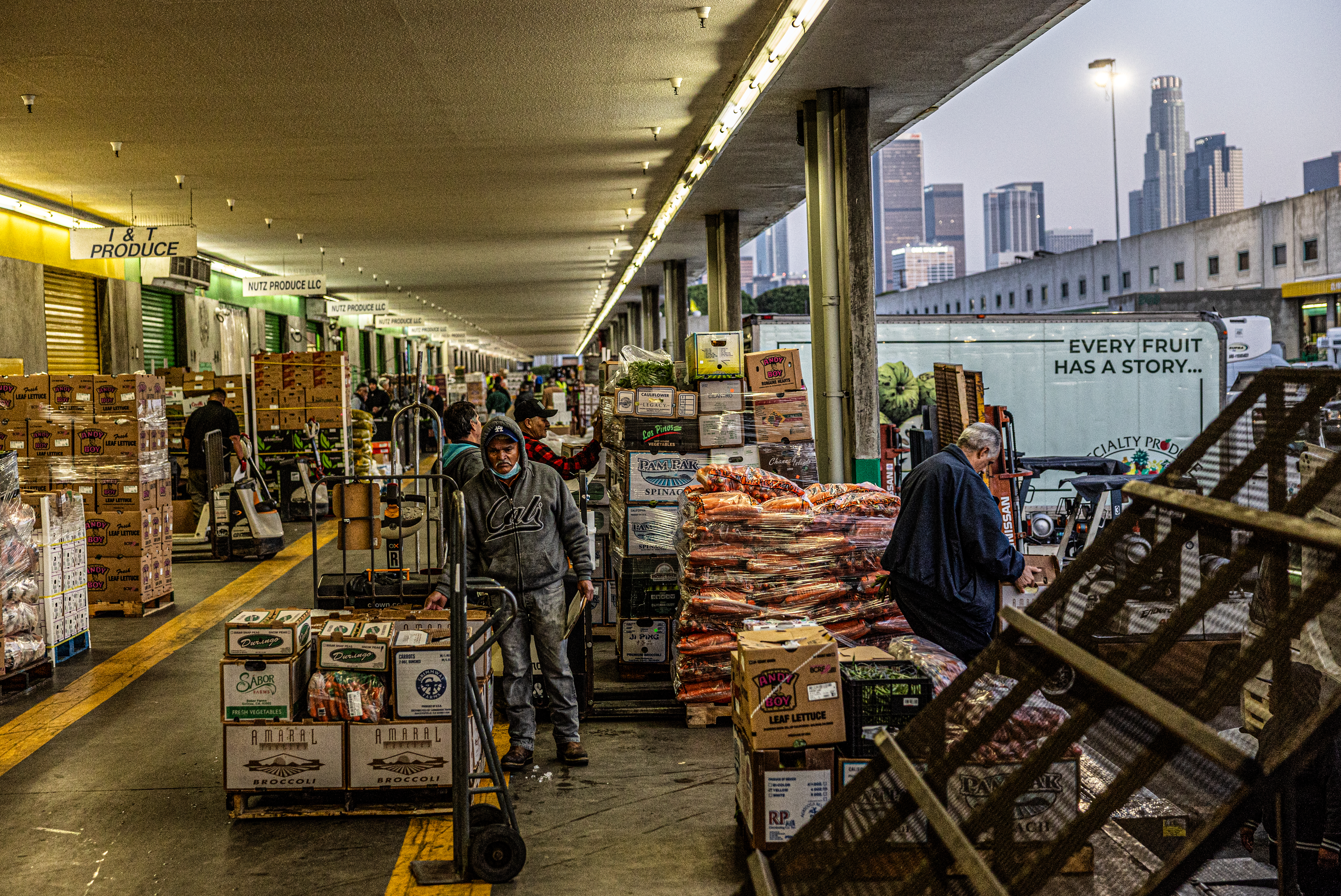 Workers move wholesale fruit on a loading doc.