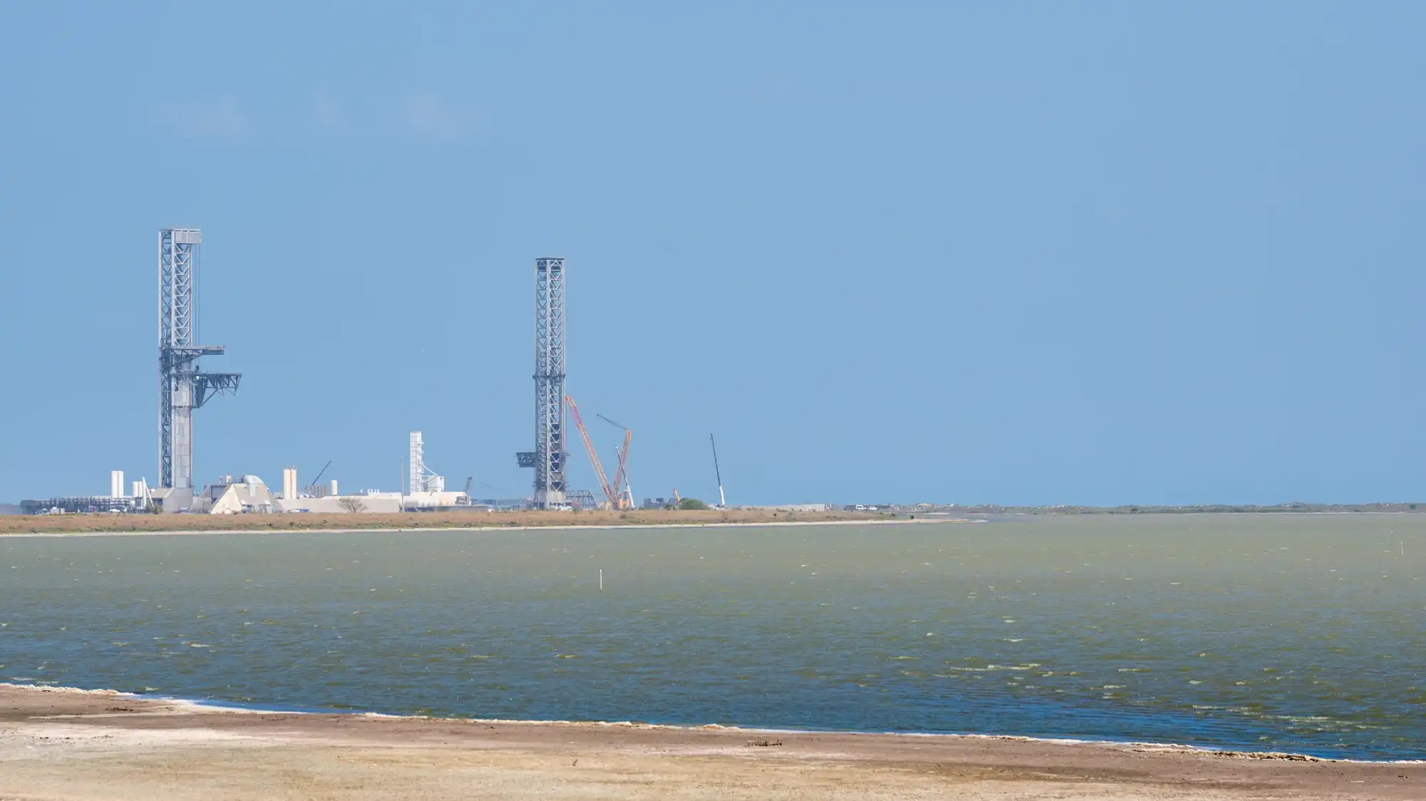 A rocket launch pad seen from a distance over water.