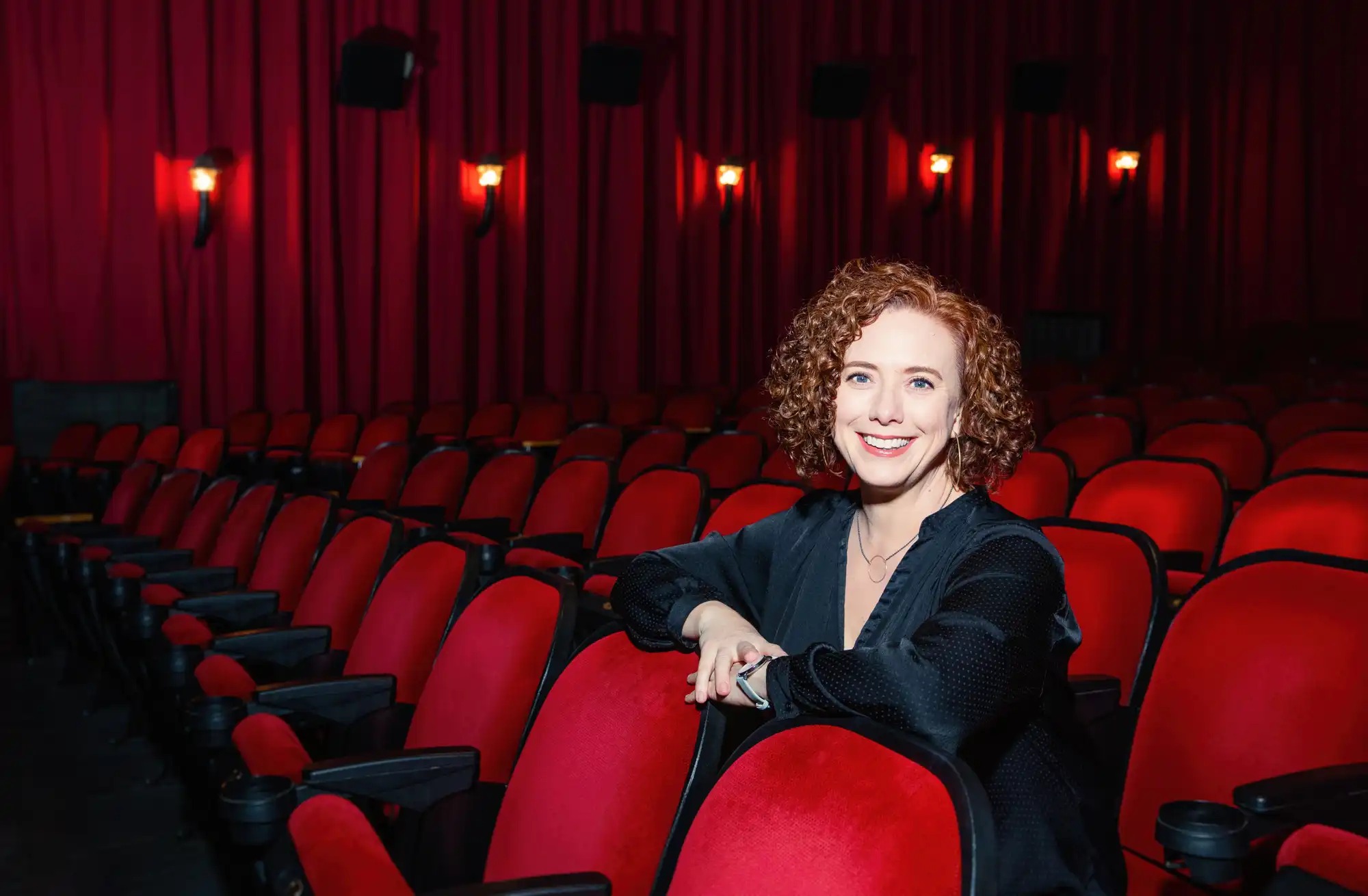 A woamn poses for a portrait in a movie theater.
