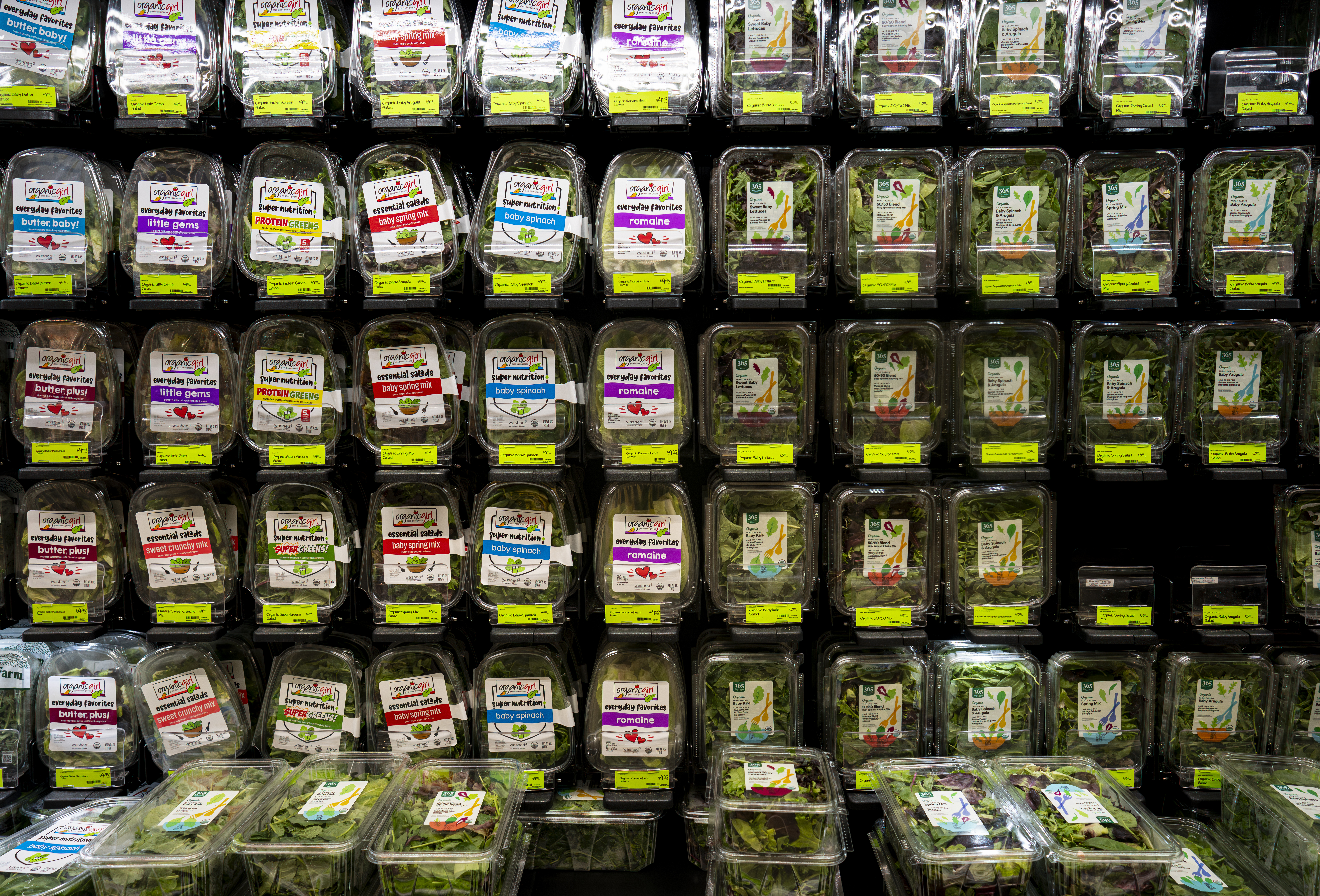 A display of plastic-packaged greens at a supermarket