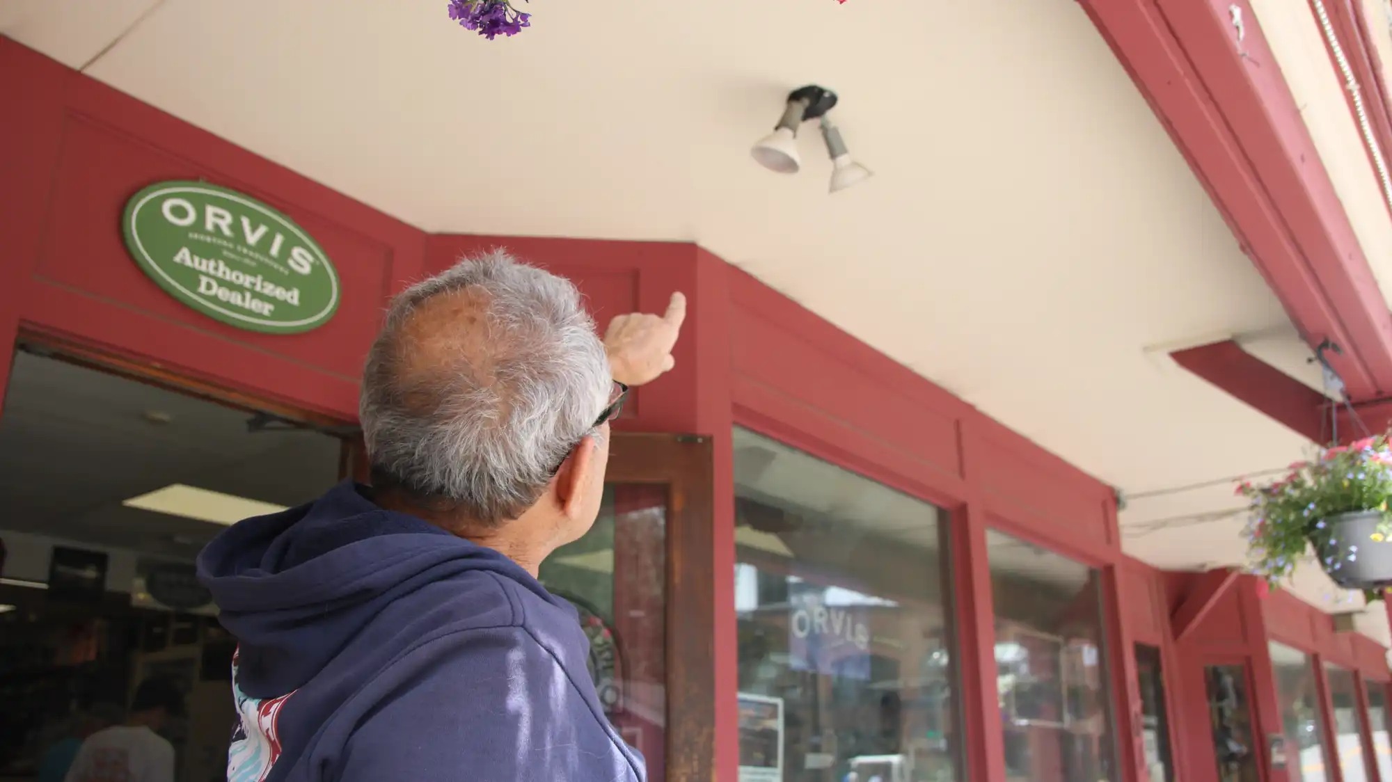 A man points at a light fixture in front of a store.