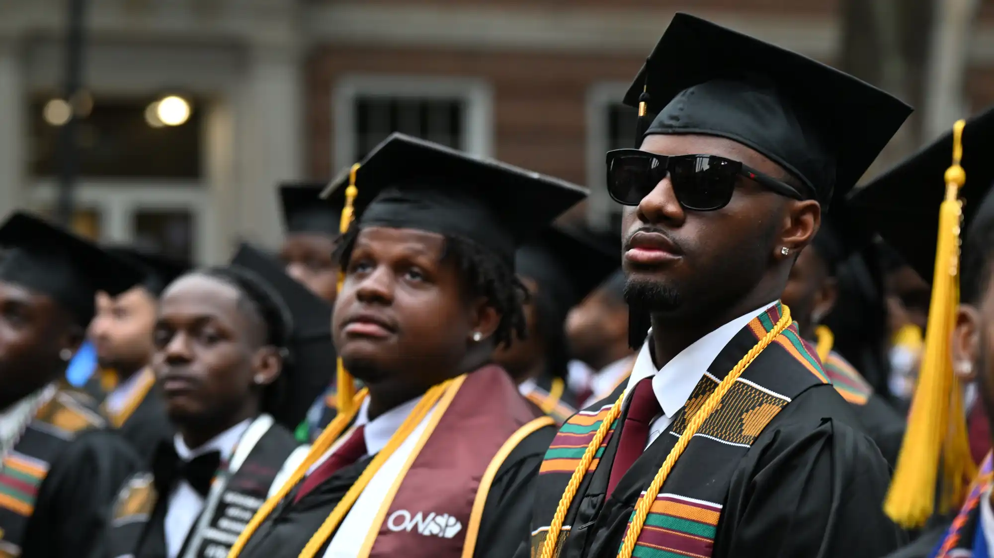 Several Black men in caps and gowns at the Millhouse College graduation ceremony last year.