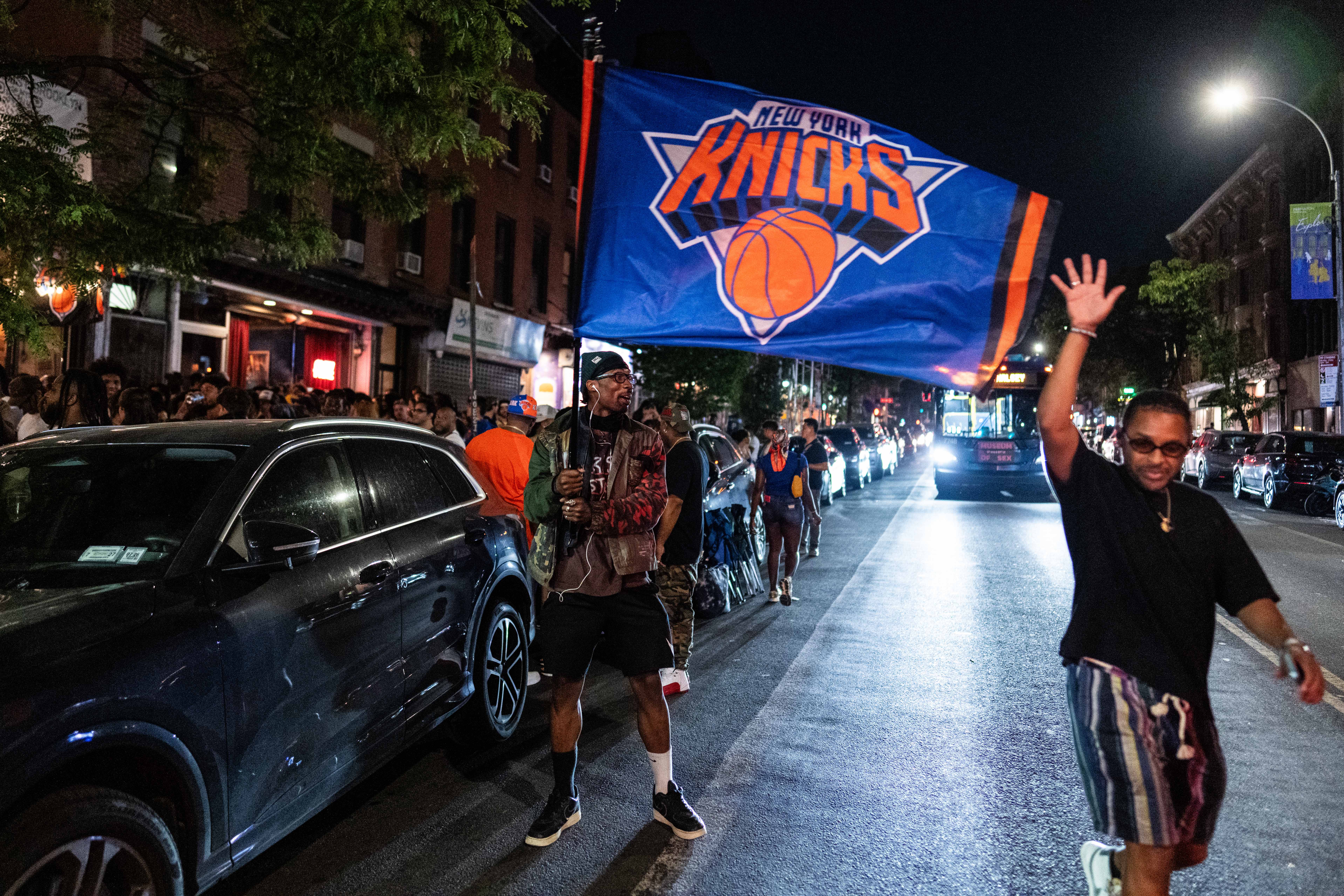 A man waves a New York Knicks flag on the streets of New York City