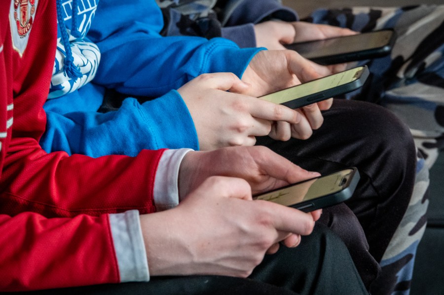 Three teenage boys looks at their smartphone screens. 