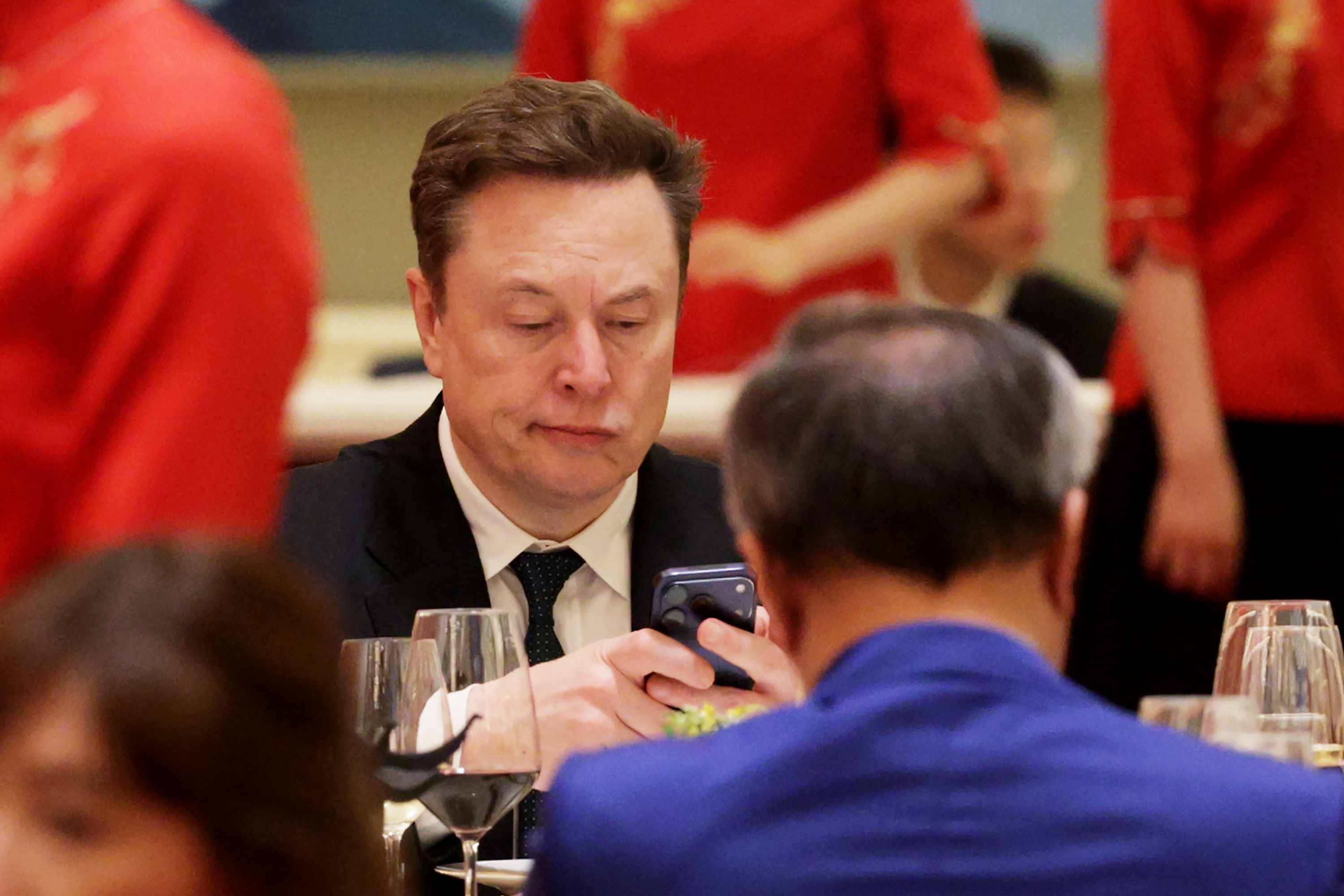 Elon Musk frowns looking at his phone. 