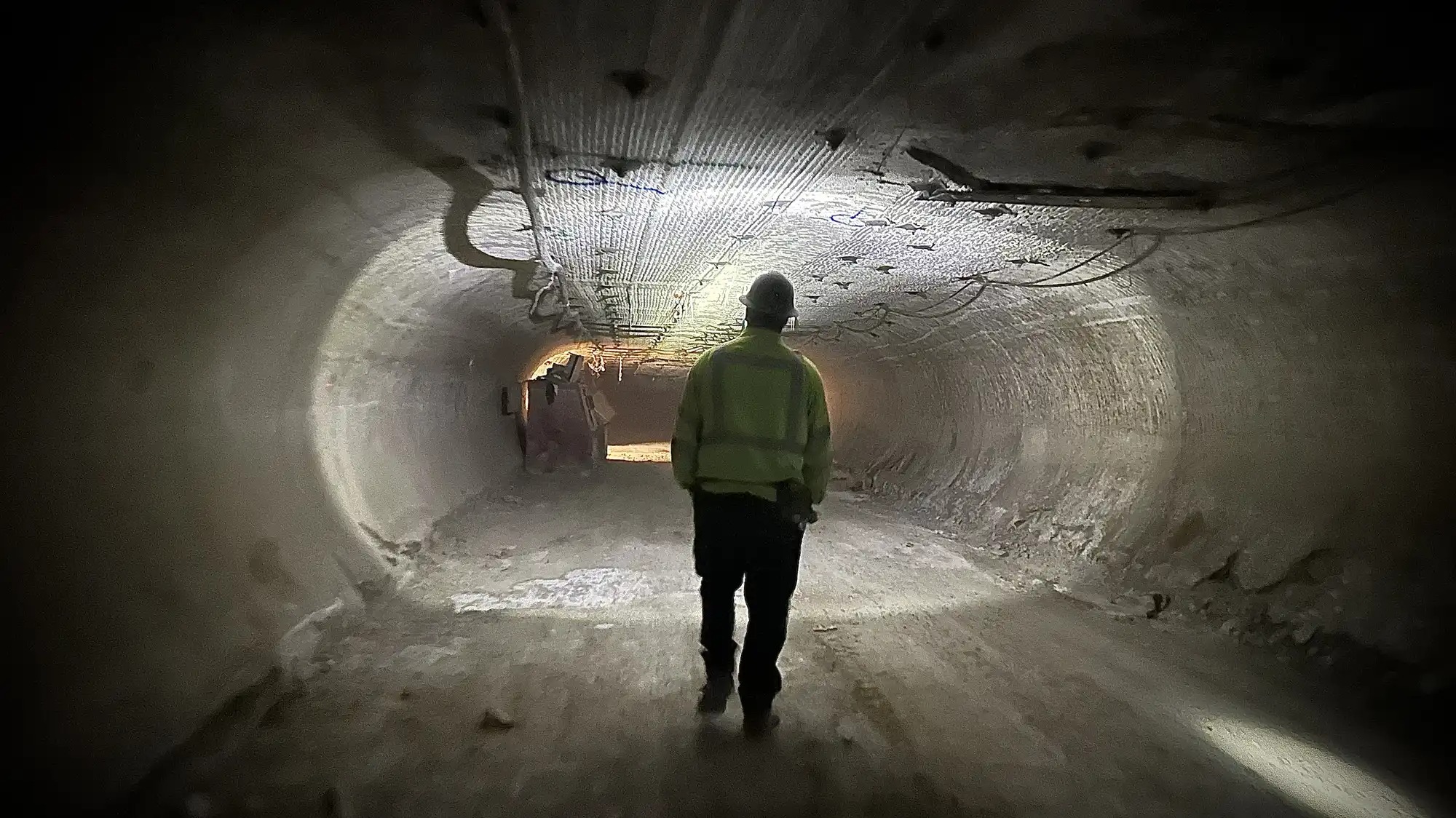 A man walks through a dark tunnel.