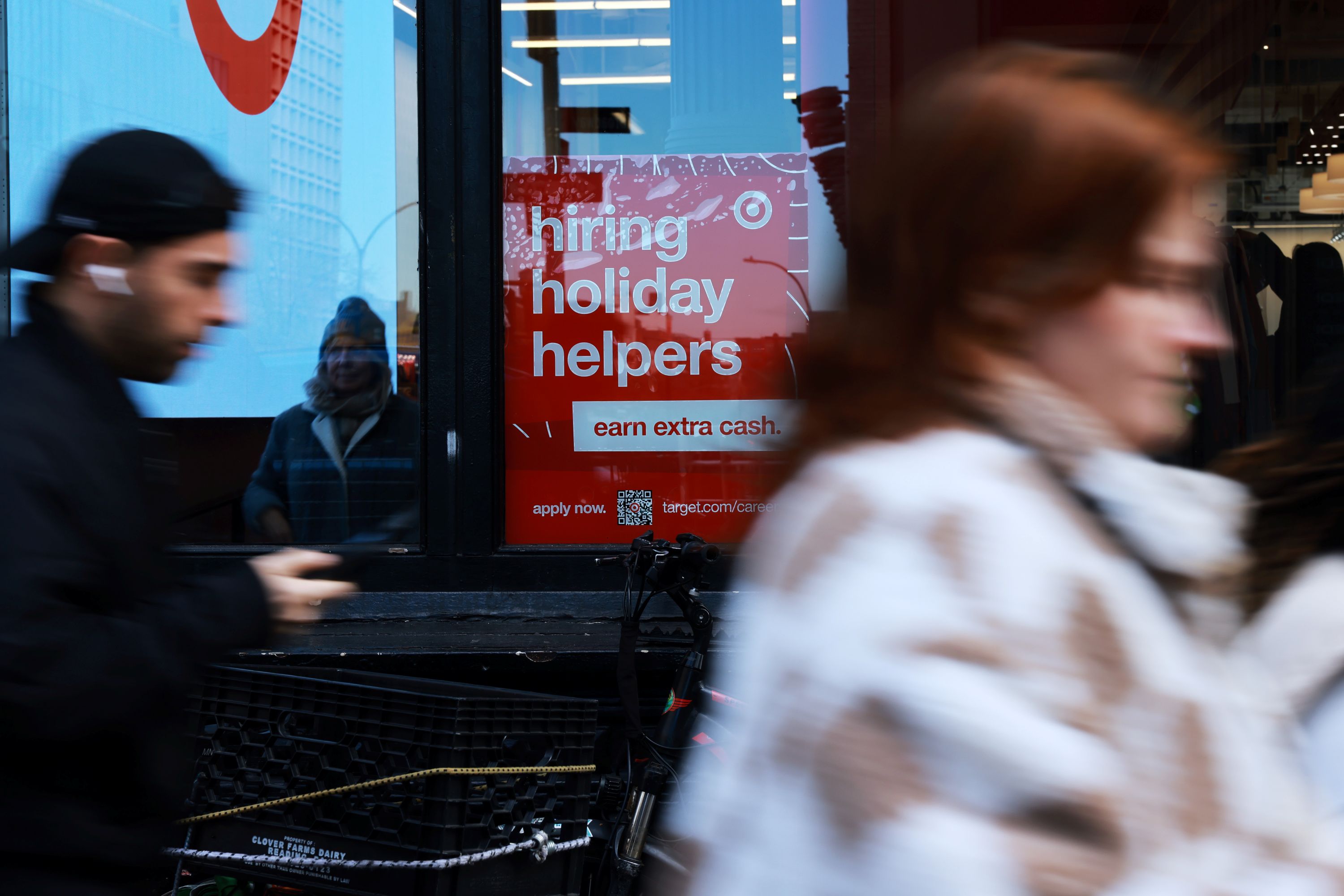 people pass a hiring holiday helpers sign
