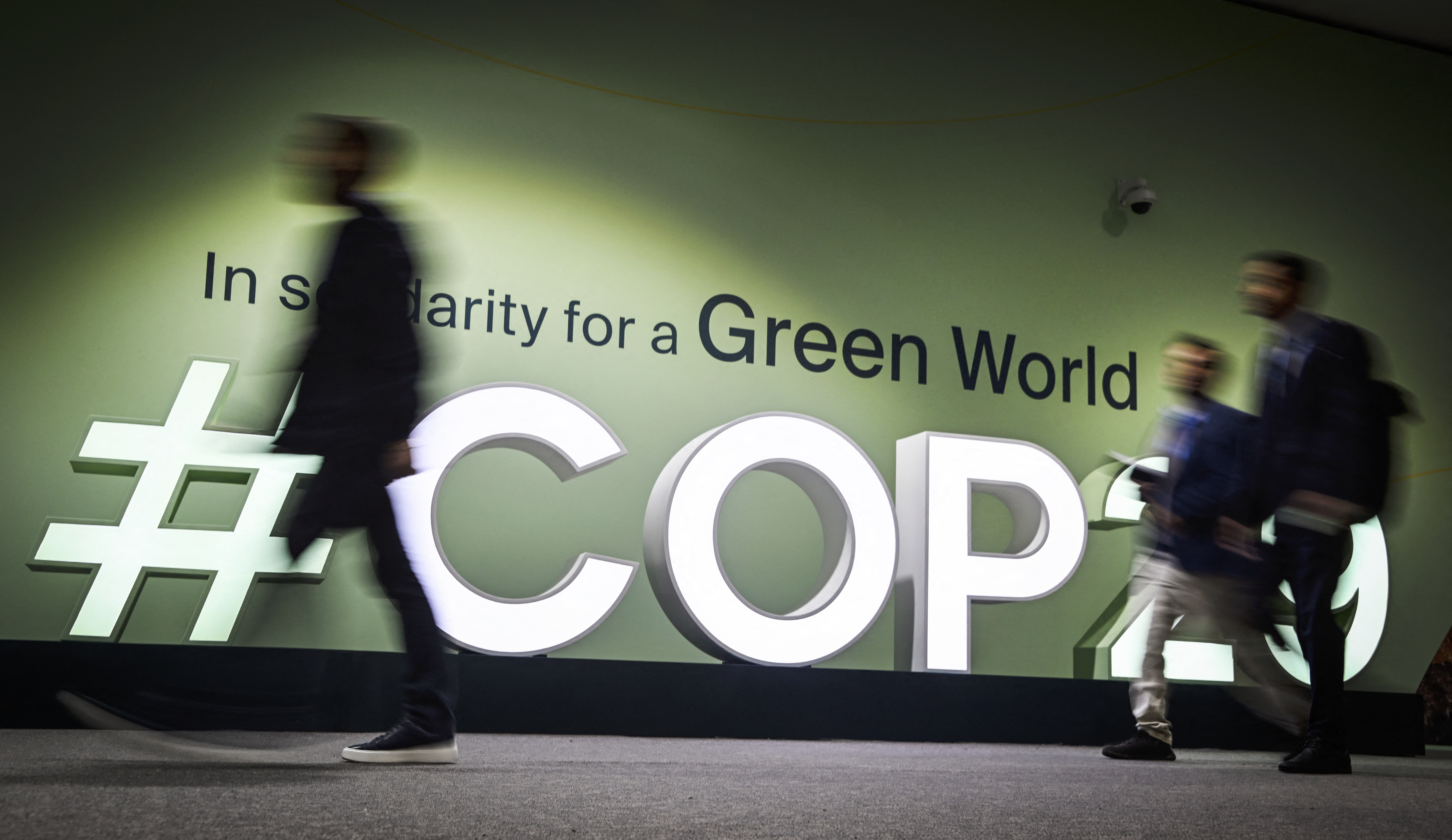 People walk past the logot at the venue for the 2024 United Nations Climate Change Conference (COP29) in Baku on Nov. 11, 2024.