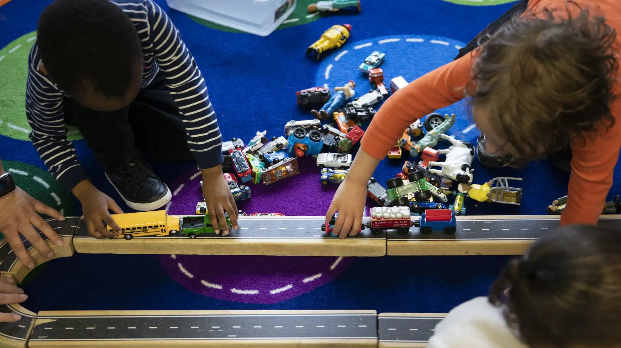 Three children playing with toy trucks.